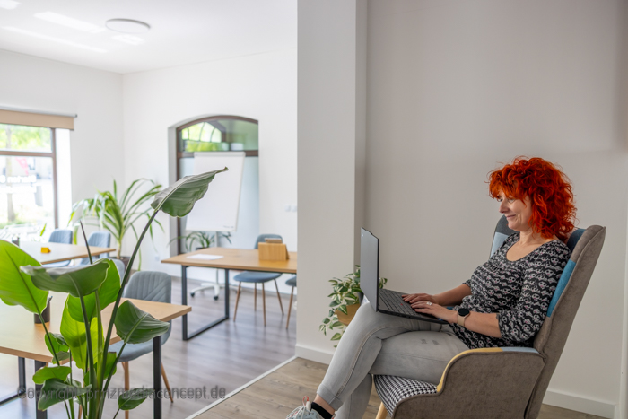 DigiUp Strausberg - Ein digitaler Ort für alle! - Moderner, offener Raum mit gemütlicher Sitzecke, runden Tischen und stilvoller Holz- und Steinwandgestaltung.